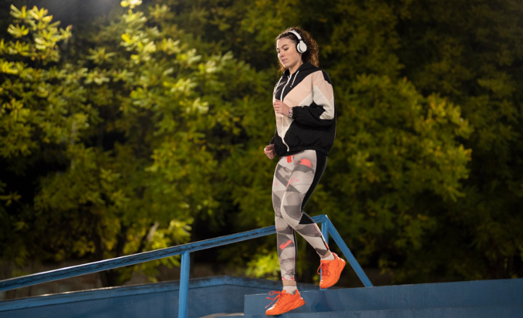 woman wearing headphones running on stairs