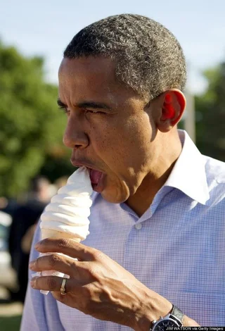 Barack Obama intensely licking a tall swirl of soft-serve ice cream in broad daylight