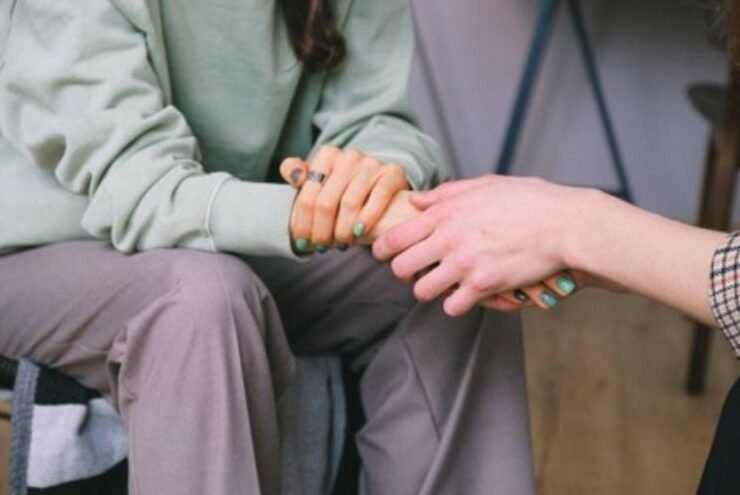 Two women holding hands in support, symbolizing care and guidance during comprehensive addiction treatment programs for recovery success.