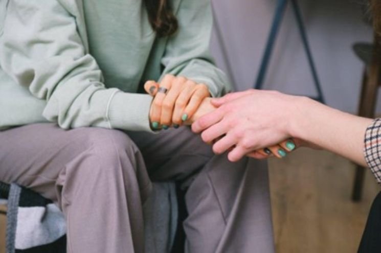 Two women holding hands in support, symbolizing care and guidance during comprehensive addiction treatment programs for recovery success.