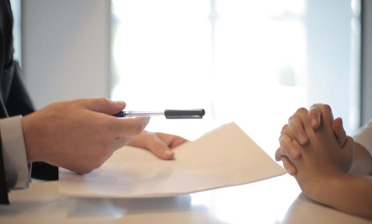 Crop businessman giving contract to woman to sign
