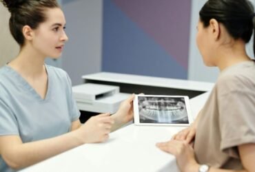 A dentist showing a dental X-ray to a patient during a consultation.