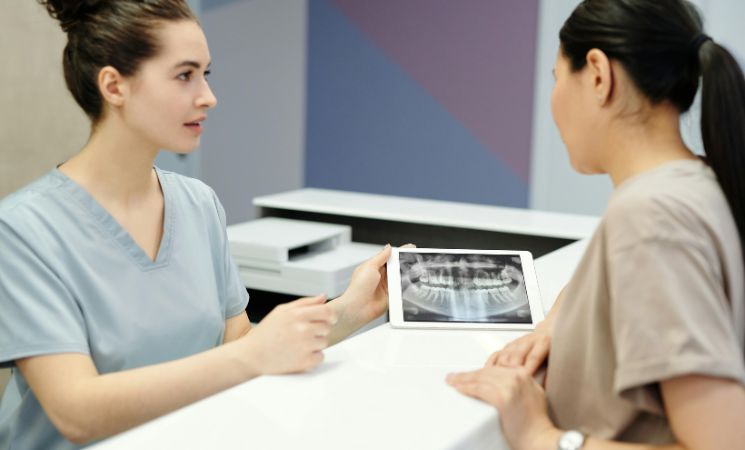 A dentist showing a dental X-ray to a patient during a consultation.