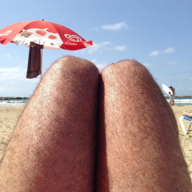 Funny beach photo where knees look like shiny bald heads — top 20 funny pictures online.
