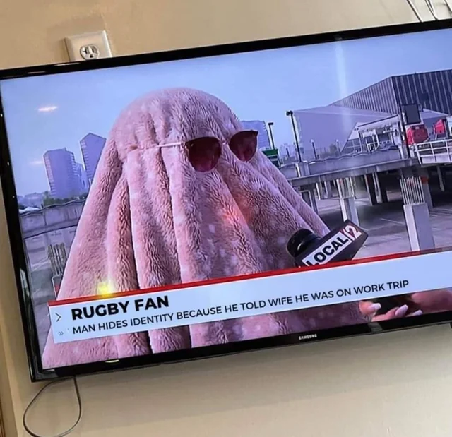 Funny image of a man fully disguised under a pink coat and sunglasses to avoid being seen at a rugby match — funny images of people being ridiculous
