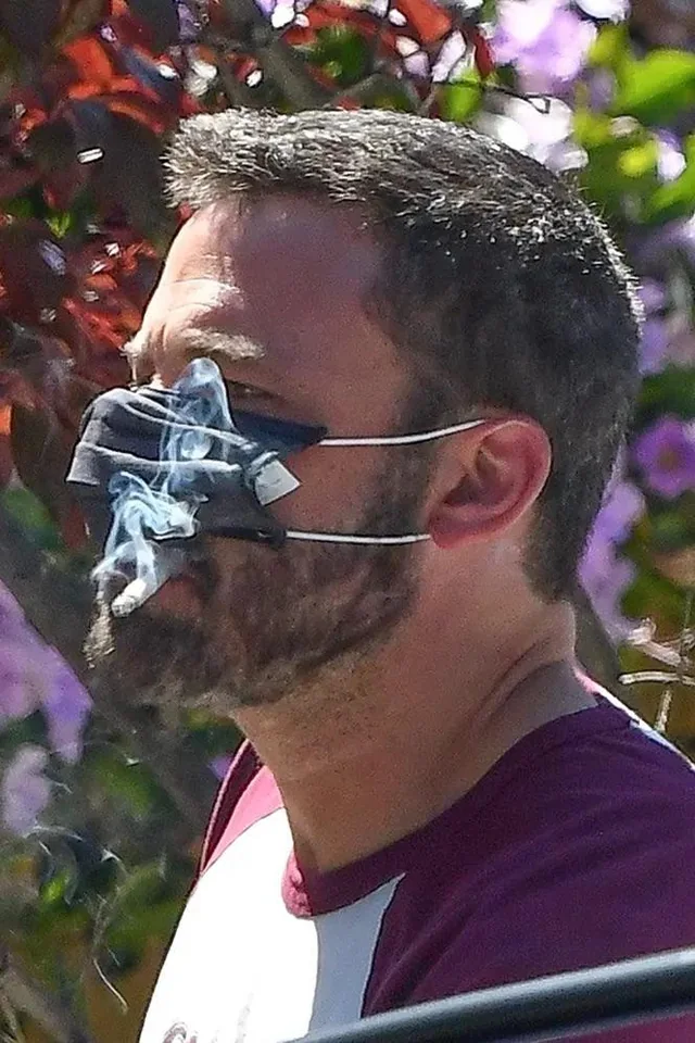 Funny photo of Ben Affleck smoking with a mask stretched awkwardly over his face — top 20 funny pictures online.