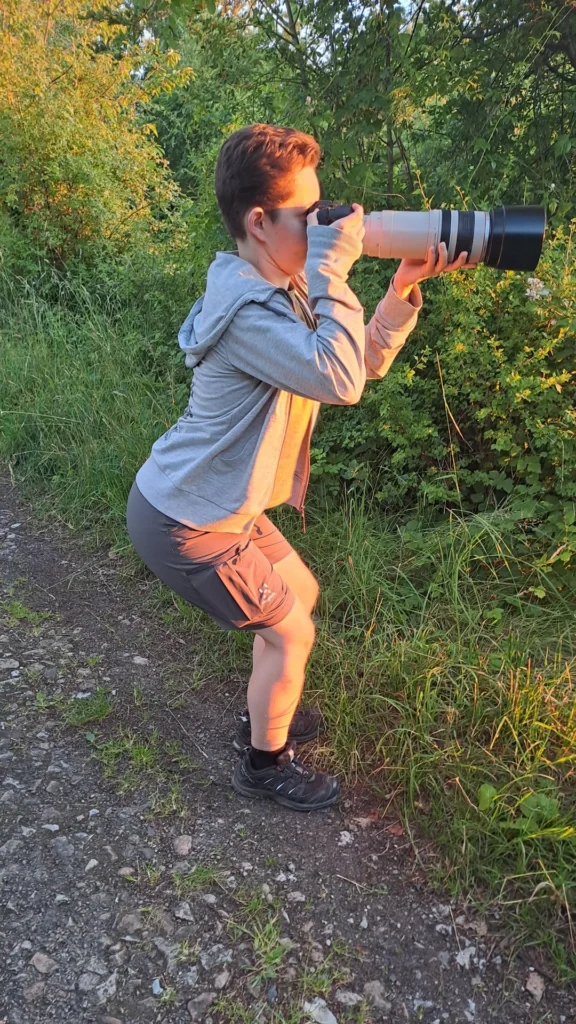 Funny image of person squatting with a huge camera lens in the woods — top 20 funniest pictures online.

