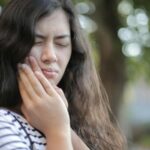 Shallow Focus on a teeth pain Photo of Woman in White and Black Stripe Shirt