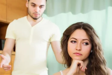 Couple having serious talking in living room - Telling my wife my childhood friend will never forgive her for what she did AITA
