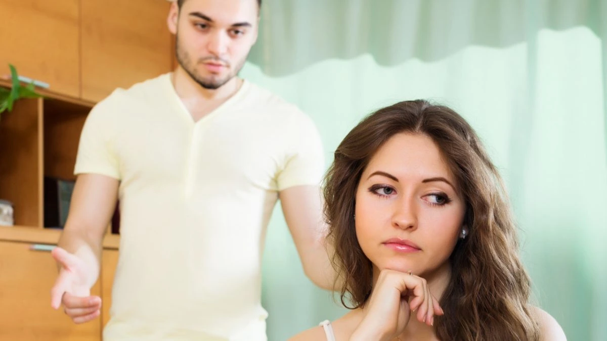 Couple having serious talking in living room - Telling my wife my childhood friend will never forgive her for what she did AITA