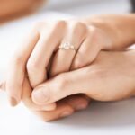 Close-up of a couple holding hands with an elegant diamond engagement ring, showcasing top diamond cut types.