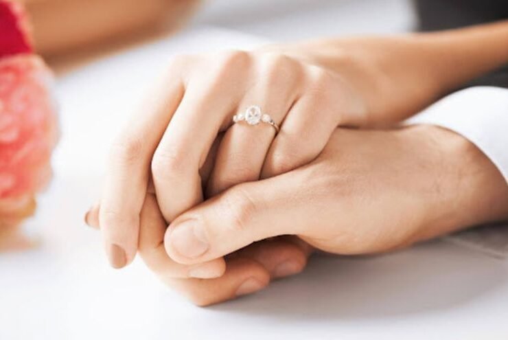 Close-up of a couple holding hands with an elegant diamond engagement ring, showcasing top diamond cut types.