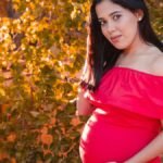 Pregnant woman in red dress representing human voice and storytelling in modern audio media