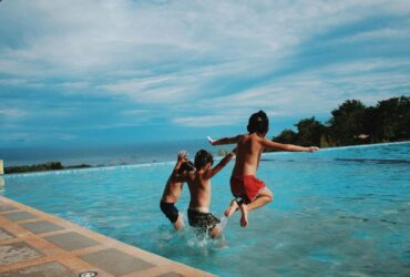 Boys jumping into water enjoying a summer social scene
