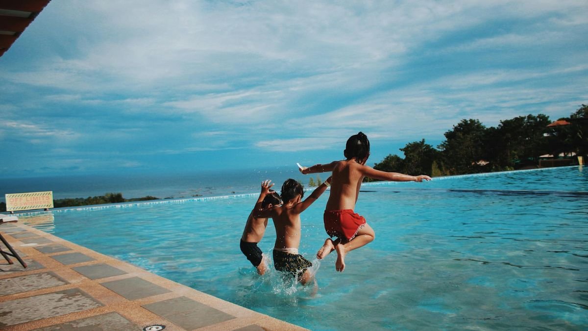 Boys jumping into water enjoying a summer social scene