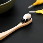 Toothbrush with toothpaste beside a bowl, representing dental care for a bright healthy smile.