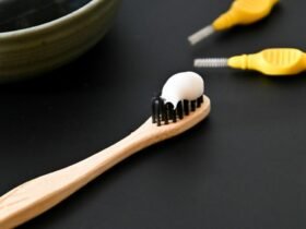 Toothbrush with toothpaste beside a bowl, representing dental care for a bright healthy smile.