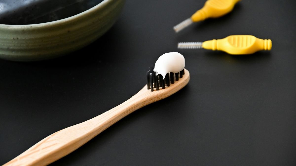 Toothbrush with toothpaste beside a bowl, representing dental care for a bright healthy smile.