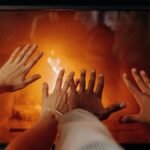 Couple’s hands near a fireplace creating a cozy winter atmosphere.