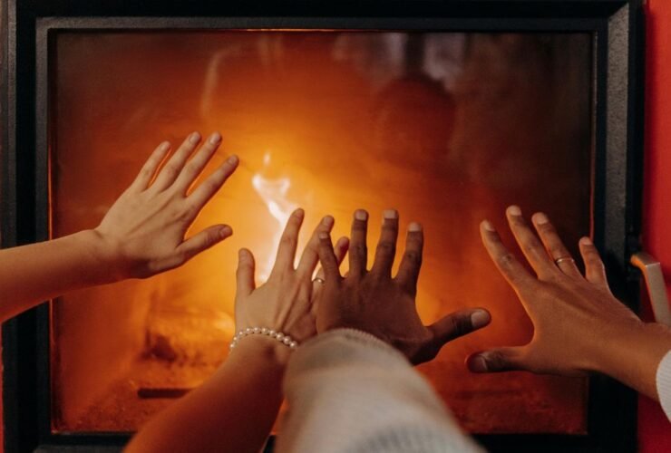 Couple’s hands near a fireplace creating a cozy winter atmosphere.