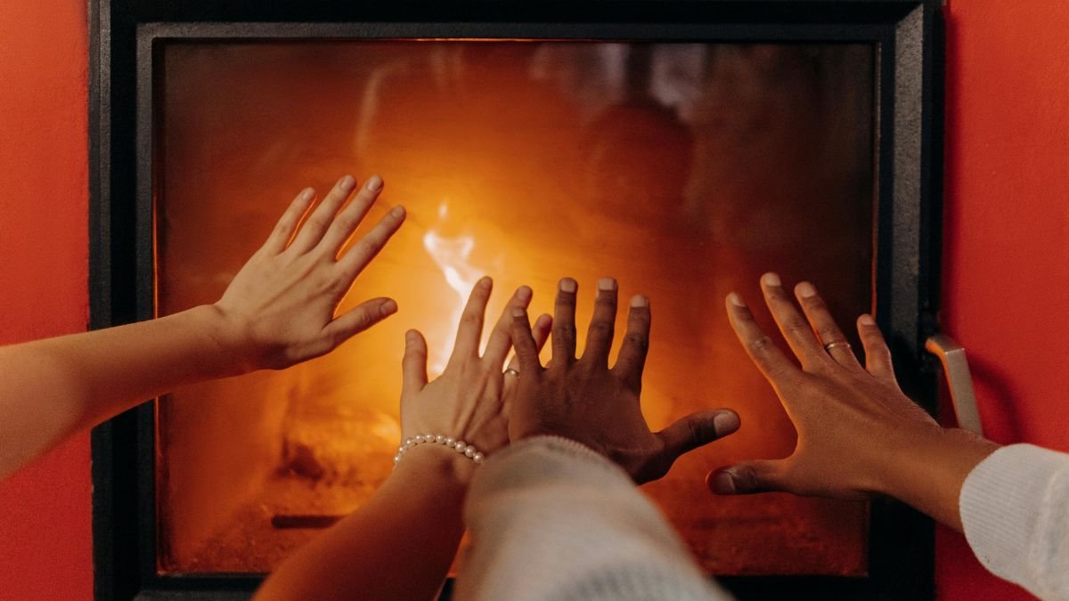 Couple’s hands near a fireplace creating a cozy winter atmosphere.