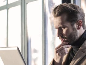 A man in an office setting, seated with a laptop on his lap, illustrates the comparison between online faxing and traditional faxing, decoding the cost benefits