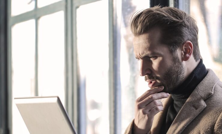 A man in an office setting, seated with a laptop on his lap, illustrates the comparison between online faxing and traditional faxing, decoding the cost benefits