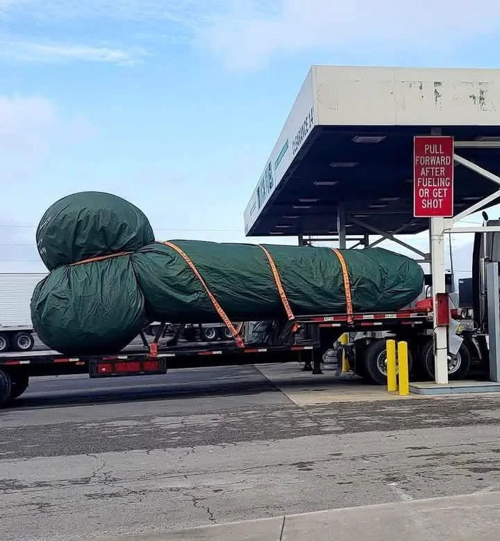 massive tarp-covered object on truck accidentally shaped like a penis with funny warning sign