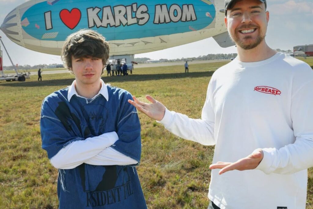 MrBeast and Karl Jacobs stand in front of a blimp with 'I ❤️ Karl's Mom' written on it, during a fun MrBeast challenge