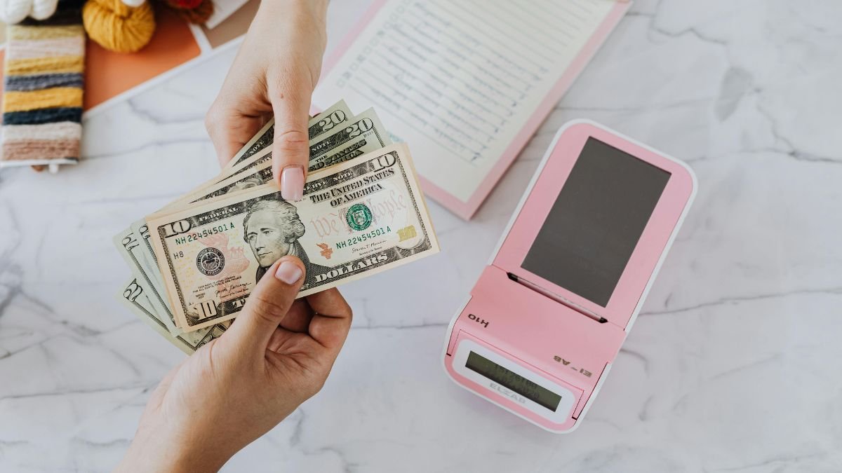 Hands holding dollar bills representing financial planning and EMI calculation