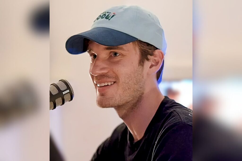 PewDiePie, real name Felix Kjellberg, wearing a blue cap and speaking into a microphone during an interview. The legendary YouTuber, standing at 5'11" (1.80 m), is about two inches shorter than MrBeast.