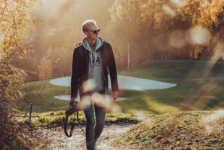 A man walking outdoors while holding a DSLR camera, capturing moments through photography.