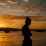 Photo by Julia Volk - Sad woman suffering with mental health standing on coast of sea at sunset