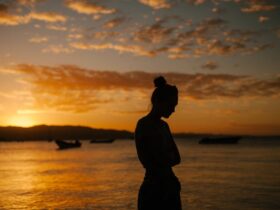 Photo by Julia Volk - Sad woman suffering with mental health standing on coast of sea at sunset