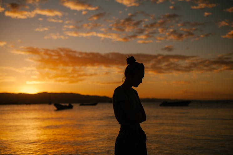 Photo by Julia Volk - Sad woman suffering with mental health standing on coast of sea at sunset