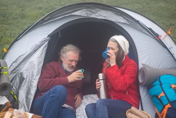 A retired couple enjoying a drink in a tent, embracing a relaxed vacation-like lifestyle.