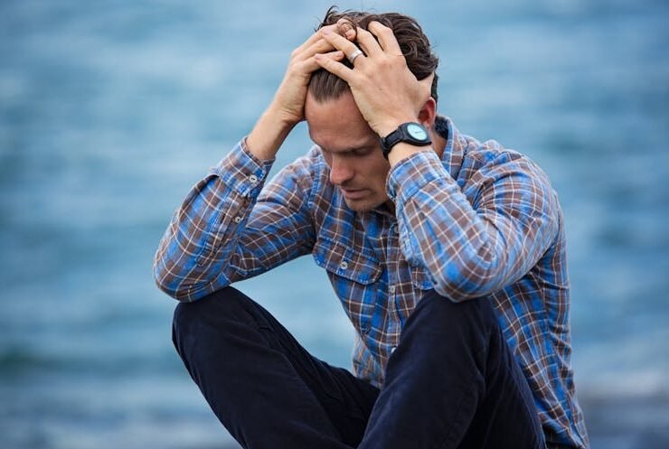 Man appearing stressed while sitting alone, possibly experiencing hidden anxiety