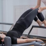 Photo by Nicholas Fu - Fitness Instructor Assisting Woman Doing Pilates