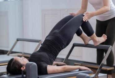 Photo by Nicholas Fu - Fitness Instructor Assisting Woman Doing Pilates