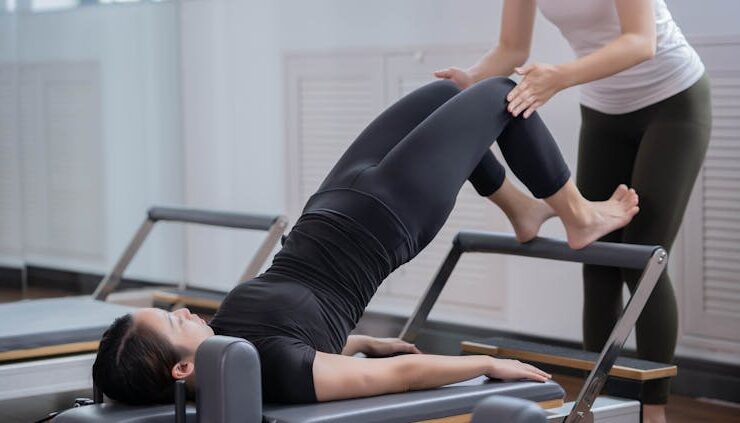 Photo by Nicholas Fu - Fitness Instructor Assisting Woman Doing Pilates