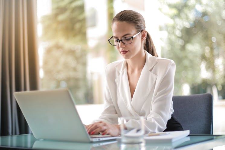 Focused female entrepreneur typing on a laptop in a workplace, representing career opportunities after completing a B Tech in Computer Science.