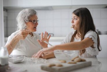 Grandmother and granddaughter talking while cooking in care home kitchen