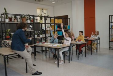 Engaged students raising hands in a busy classroom environment