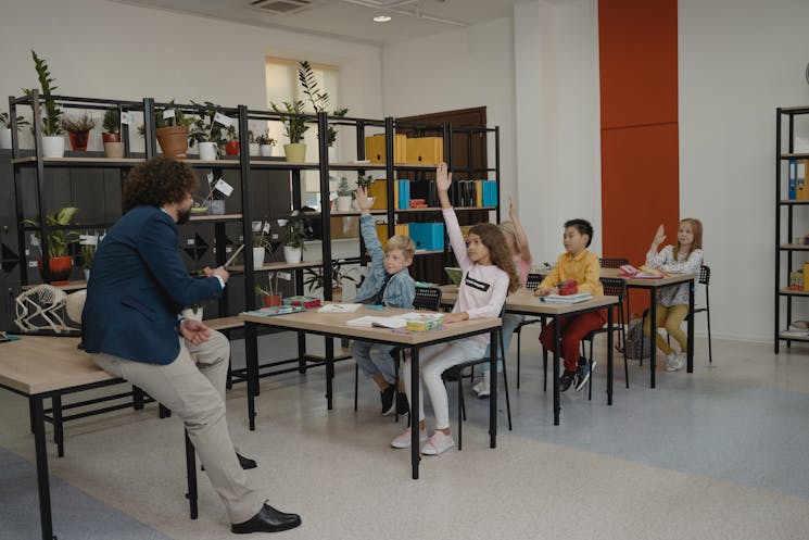 Engaged students raising hands in a busy classroom environment