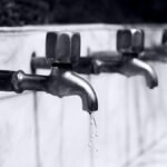 Water dripping from a household faucet representing plumbing issues.