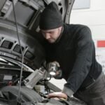 Man checking car engine during road trip preparation