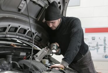 Man checking car engine during road trip preparation