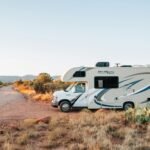 White and brown RV parked on an open field under clear daylight, symbolizing freedom and adventure on the open road.