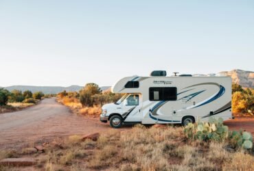 White and brown RV parked on an open field under clear daylight, symbolizing freedom and adventure on the open road.