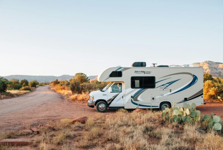 White and brown RV parked on an open field under clear daylight, symbolizing freedom and adventure on the open road.